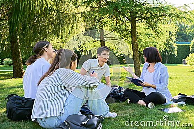 Group of high school students with female teacher, on campus lawn Stock Photo