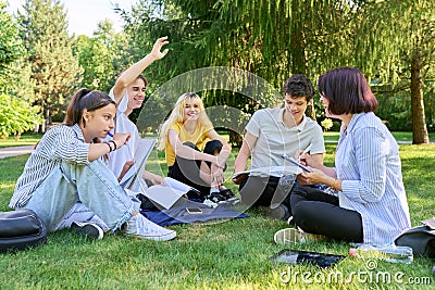 Group of high school students with female teacher, on campus lawn Stock Photo