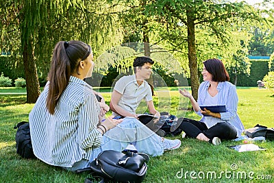 Group of high school students with female teacher, on campus lawn Stock Photo