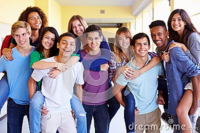 Group Of High School Students Giving Piggybacks In Corridor Stock Photo