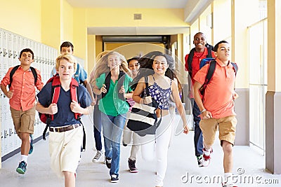 Group Of High School Students Running Along Corridor Stock Photo