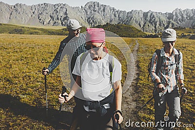 Group Of Hikers Walking Along The Plain In Summer Mountains, Journey Travel Trek Concept Stock Photo