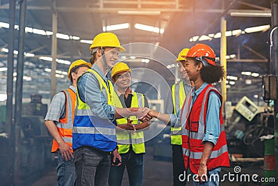 A group of industry workers and engineers of various races enjoy working in a heavy plant and stand together with a pleasant smile Stock Photo