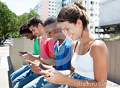 Group of international young adults typing message at phone Stock Photo