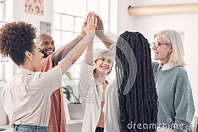 Group of joyful diverse businesspeople giving each other a high five in an office at work. Business professionals having Stock Photo