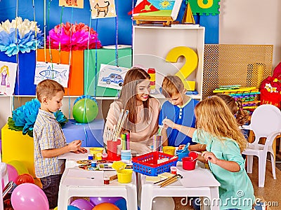 Group of kids with female teacher painting together . Stock Photo