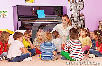 Group of kids sit and listen to teacher tell story Stock Photo