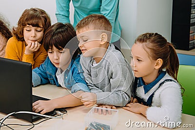 group of kids working with laptop together while teacher standing Stock Photo