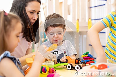 Group of kindergarten children playing with plasticine or dough at daycare. Stock Photo