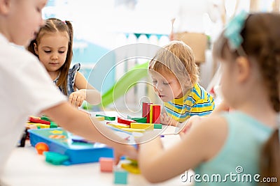 Group of kindergarten kids at day care. Happy children playing with plastic building blocks at kindergarten Stock Photo