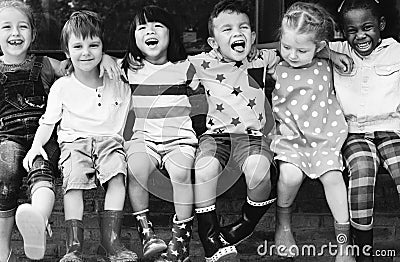 Group of kindergarten kids friends arm around sitting and smiling fun Stock Photo