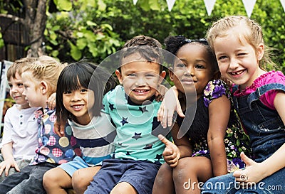 Group of kindergarten kids friends arm around sitting and smiling fun Stock Photo