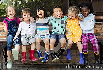 Group of kindergarten kids friends arm around sitting and smiling fun Stock Photo