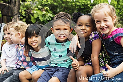 Group of kindergarten kids friends arm around sitting and smiling fun Stock Photo