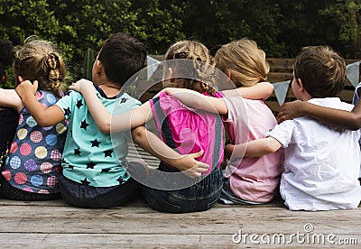 Group of kindergarten kids friends arm around sitting together Stock Photo