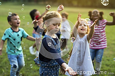 Group of kindergarten kids friends playing blowing bubbles fun Stock Photo