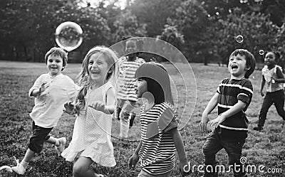 Group of kindergarten kids friends playing blowing bubbles fun Stock Photo