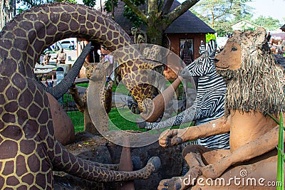 Group of large wooden handcrafted sculptures of lion, giraffe, zebra and leopard in the garden of Cultural Heritage store in Stock Photo