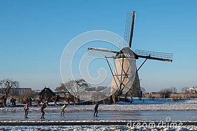 Group of locals on a frozen windmill canal pathway at sunrise moment Editorial Stock Photo