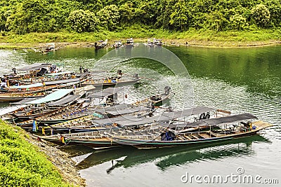 Group long-tail boat landscape with background mountains trees and mist and a lake in front,Evening. Stock Photo