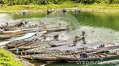 Group long-tail boat landscape with background mountains trees and mist and a lake in front,Evening after heavy rainy day. Editorial Stock Photo
