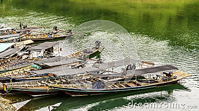 Group long-tail boat landscape with background mountains trees and mist and a lake in front,Evening after heavy rainy day Stock Photo