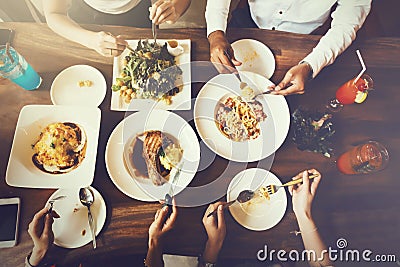 Group of male and female friends having dinner and eating steak and salad and spaghetti together in restaurant - top view. Stock Photo