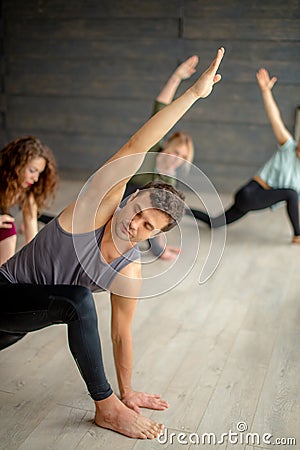 Yoga beginners exercising against grey wall, doing yoga or pilates posture. Stock Photo