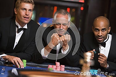 Group of male friends gambling at roulette table Stock Photo