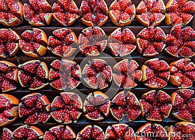 A group of many pomegranate fruit cut in pieces divided equally in sections forming background Stock Photo