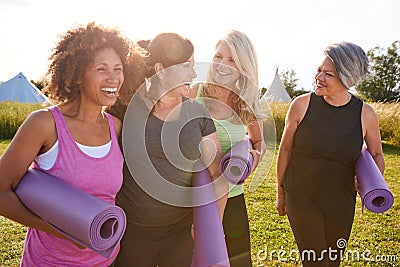 Group Of Mature Female Friends On Outdoor Yoga Retreat Walking Along Path Through Campsite Stock Photo
