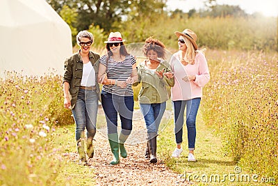 Group Of Mature Female Friends Walking Along Path Through Yurt Campsite Stock Photo