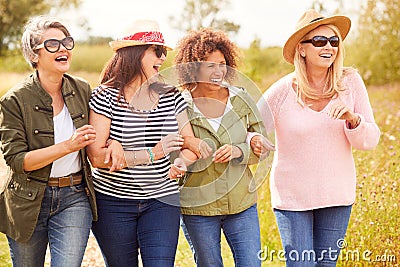 Group Of Mature Female Friends Walking Along Path Through Yurt Campsite Stock Photo