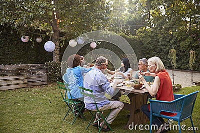 Group Of Mature Friends Enjoying Outdoor Meal In Backyard Stock Photo