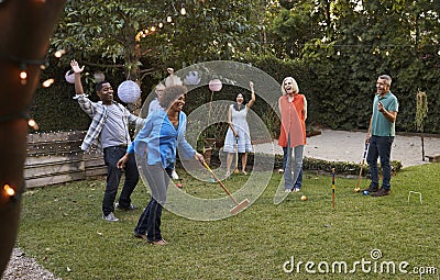 Group Of Mature Friends Playing Croquet In Backyard Together Stock Photo