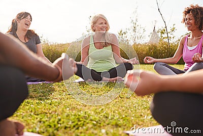 Group Of Mature Men And Women In Class At Outdoor Yoga Retreat Sitting Circle Meditating Stock Photo