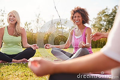 Group Of Mature Men And Women In Class At Outdoor Yoga Retreat Sitting Circle Meditating Stock Photo