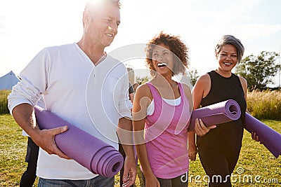 Group Of Mature Men And Women With Exercise Mats At End Of Outdoor Yoga Class Stock Photo