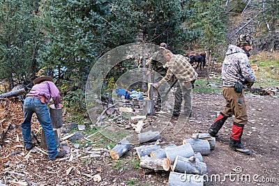 Group of men hunters chop and split logs and wood for campfires, while on an elk hunting Editorial Stock Photo