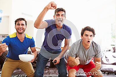 Group Of Men Sitting On Sofa Watching Sport Together Stock Photo