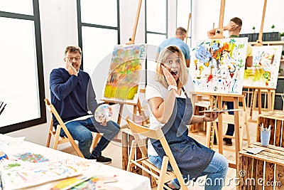 Group of middle age artist at art studio afraid and shocked, surprise and amazed expression with hands on face Stock Photo