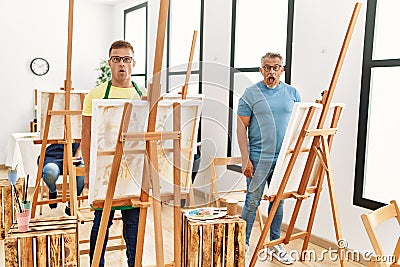 Group of middle age people artist at art studio scared and amazed with open mouth for surprise, disbelief face Stock Photo