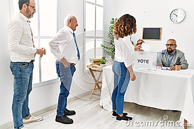 Group of middle age voter people putting vote in ballot standing at electoral center Stock Photo