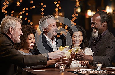 Group Of Middle Aged Friends Celebrating In Bar Together Stock Photo