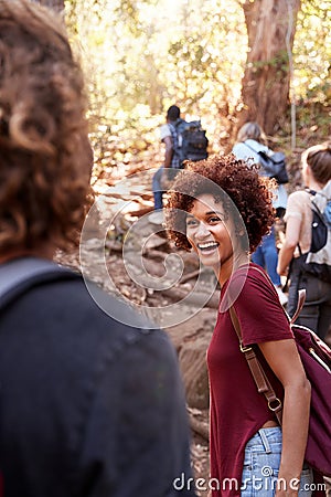 Group of millennial friends hiking up hill on a forest trail, vertical Stock Photo