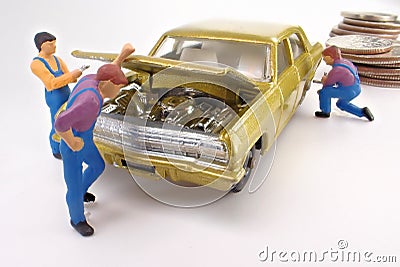 Miniature mechanics work on a gold toy car. Stock Photo