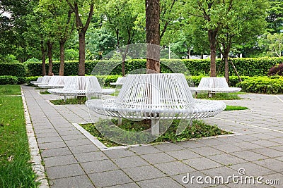Group of modern iron circle shaped benches installed around tree for resting in city park Stock Photo