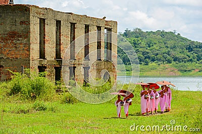 Group of Mon nuns walking out of ruined Buddhist church Editorial Stock Photo