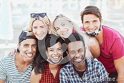 Group of multiracial friends taking a picture while focusing the camera and smiling with face mask - New lifestyle concept Stock Photo