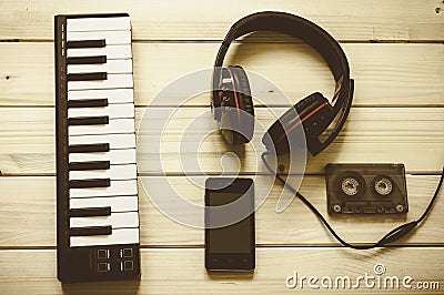 Group of musical items including a pair of headphones, a vintage cassette tape, keyboard and a phone Stock Photo